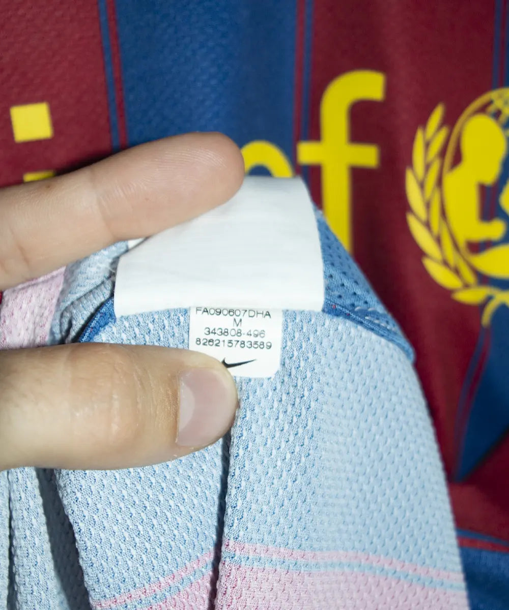Maillot domicile du fc barcelone de la saison 2009-2010. Le maillot est de couleur bleu et rouge. On peut retrouver l'équipementier nike et le sponsor unicef. Le maillot est floqué du numéro 9 Zlatan Ibrahimovic. Sur cette photo on peut retrouver l'étiquette comportant les numéros 343808-496