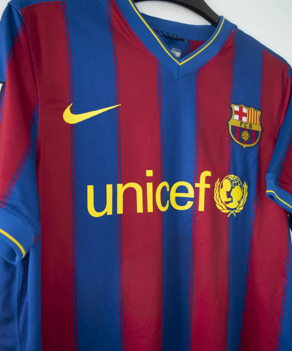 Maillot domicile du barca de la saison 2009-2010. Le maillot est de couleur bleu et rouge. On peut retrouver l'équipementier nike et le sponsor unicef. Le maillot est floqué du numéro 10 Messi