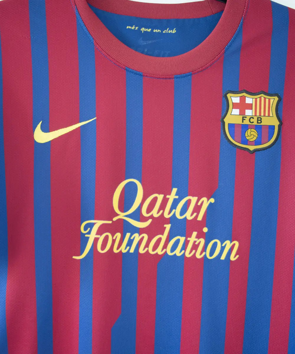 Maillot domicile bleu et rouge du fc barcelone de la saison 2011-2012. On peut retrouver le sponsor qatar foundation, le sponsor unicef et l'équipementier nike. Le maillot est floqué du numéro 10 Leo Messi. Sur cette photo on peut voir le devant du maillot de près