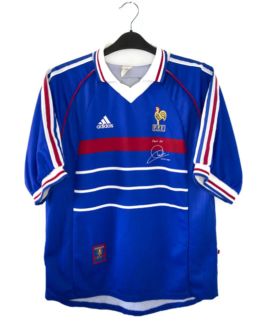 Maillot de foot vintage domicile bleu blanc et rouge de l'équipe de france 1998. On peut retrouver l'équipementier adidas. Le maillot possède la signature pour toi zinedine zidane. Il s'agit d'un maillot authentique