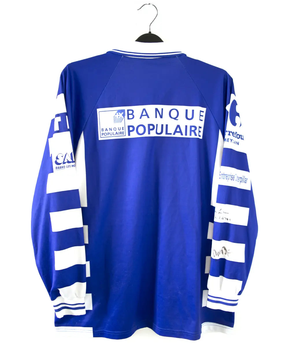 Maillot domicile de grenoble de la saison 1999/2000 de dos. On peut retrouver l'équipementier duarig et le sponsor sodexo. Le maillot est de couleur bleu et blanc.