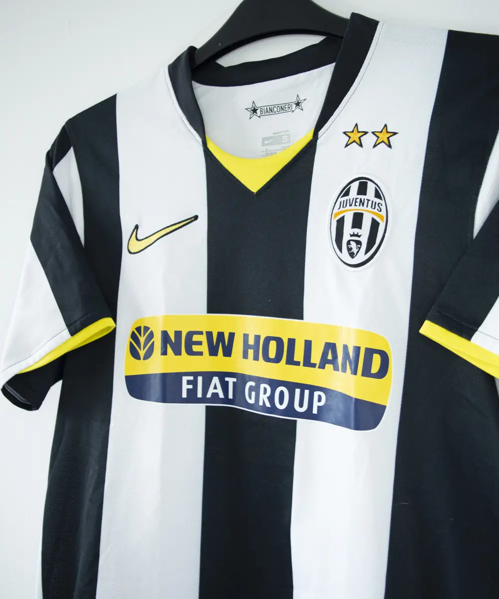 Maillot vintage domicile noir, blanc et jaune, de la juventus de la saison 2008-2009. On peut retrouver l'équipementier nike et le sponsor new holland