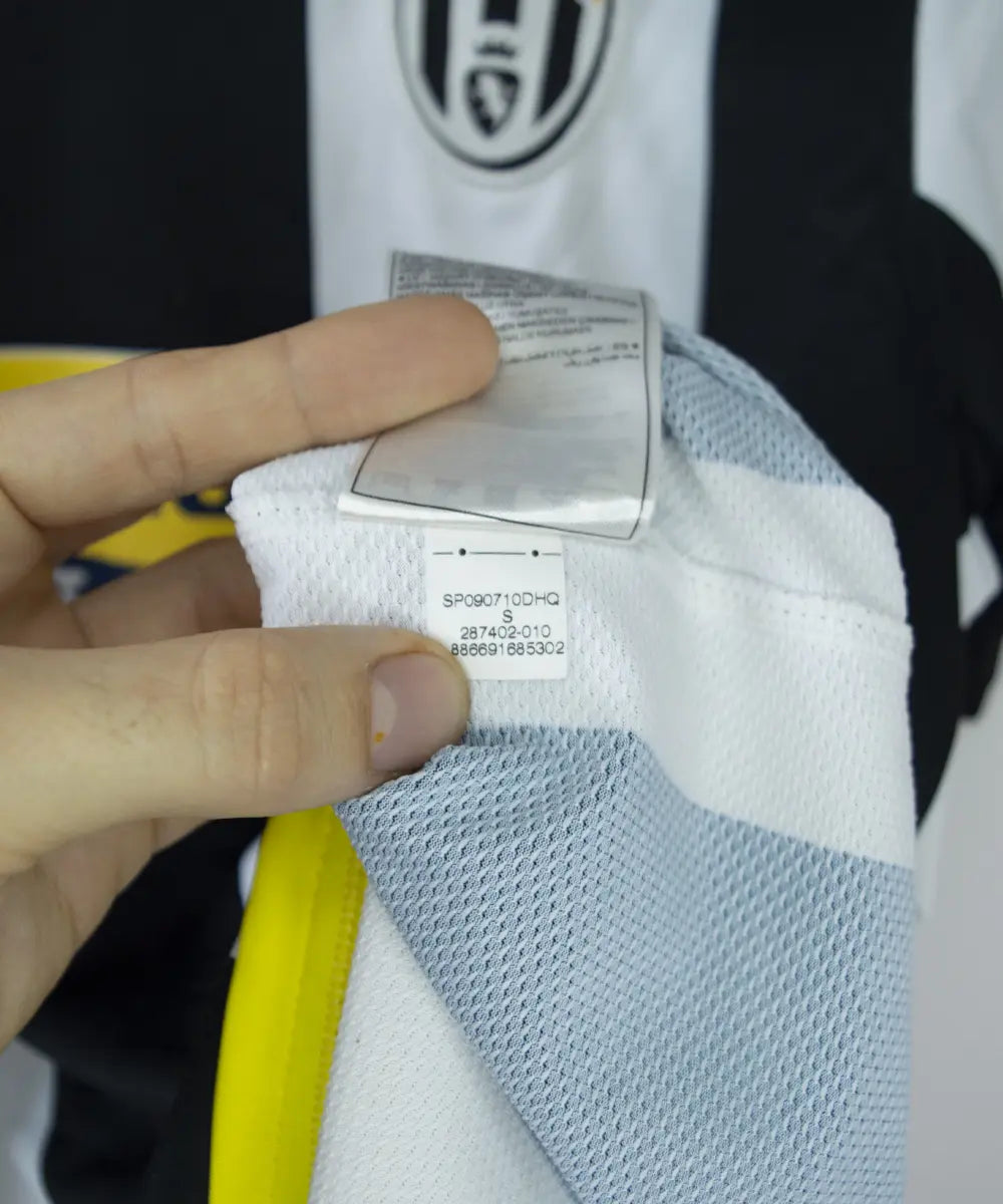 Maillot vintage domicile noir, blanc et jaune, de la juventus de la saison 2008-2009. On peut retrouver l'équipementier nike et le sponsor new holland. On peut voir l'étiquette comportant les numéros 287402-010