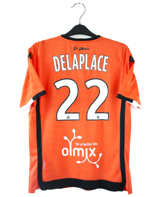 Maillot domicile de Lorient de la saison 2018-2019 de couleur orange, blanc et noir. On peut retrouver l'équipementier kappa et les sponsors jean floc'h, b&b et breizh cola. Le maillot est floqué du numéro 22 delaplace et signé par plusieurs joueurs de l'équipe