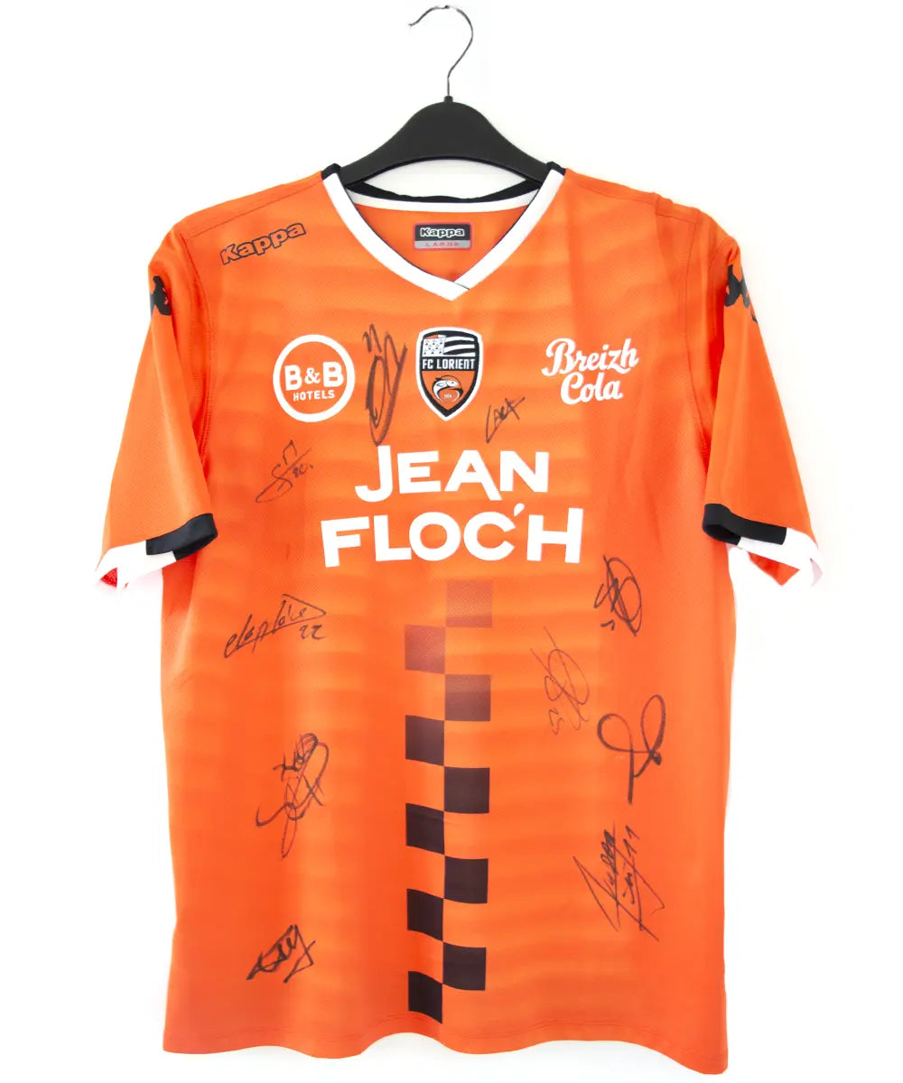 Maillot domicile de Lorient de la saison 2018-2019 de couleur orange, blanc et noir. On peut retrouver l'équipementier kappa et les sponsors jean floc'h, b&b et breizh cola. Le maillot est floqué du numéro 22 delaplace et signé par plusieurs joueurs de l'équipe