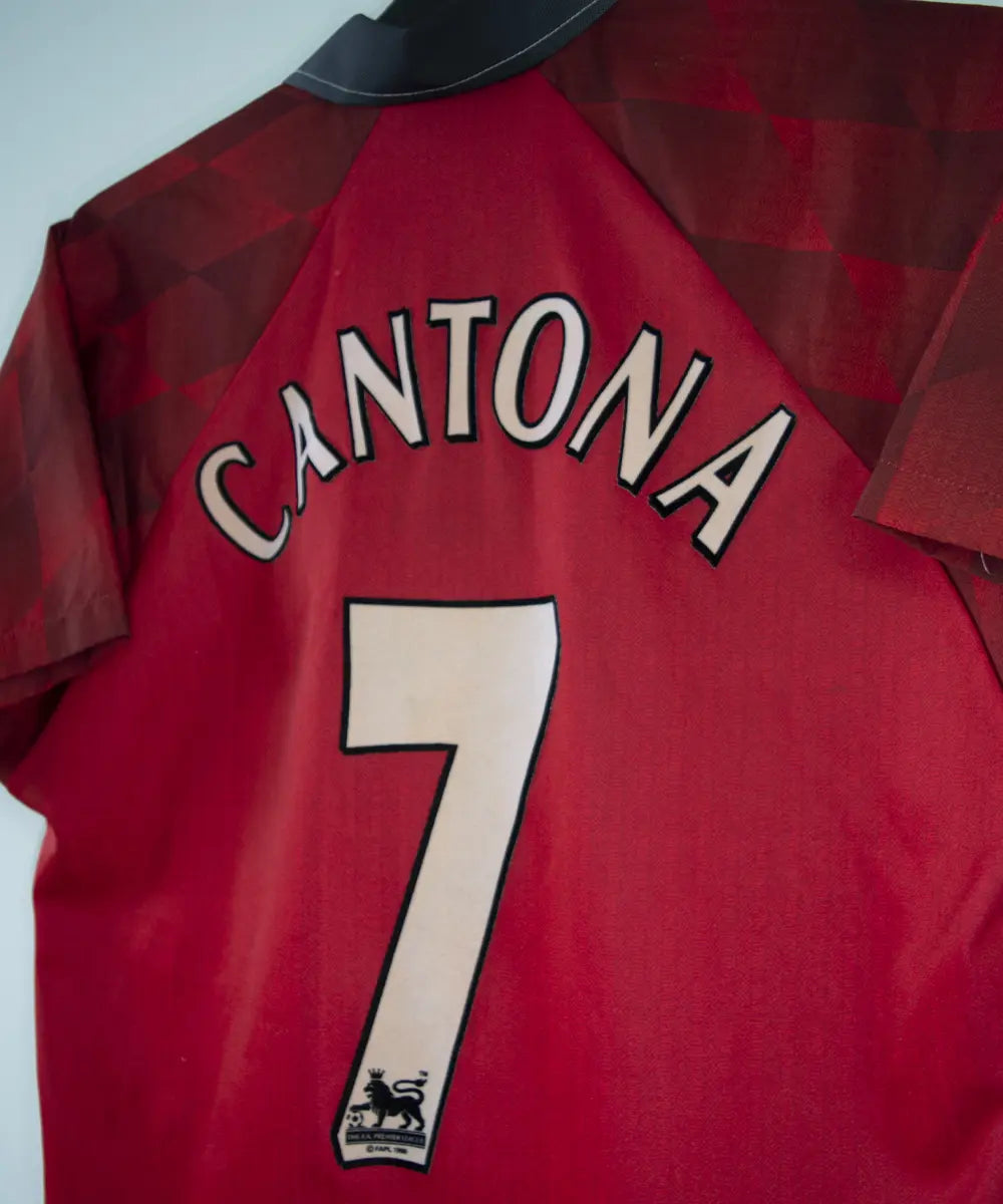 Maillot de foot vintage domicile rouge de manchester united de la saison 1996-1998. On peut retrouver l'équipementier umbro et le sponsor sharp. Le maillot est floqué du numéro 7 Cantona. Il s'agit d'un maillot authentique