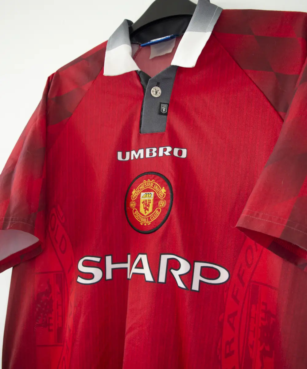 Maillot domicile vintage rouge de manchester united de la saison 1996-1998. On peut retrouver l'équipementier umbro et le sponsor sharp