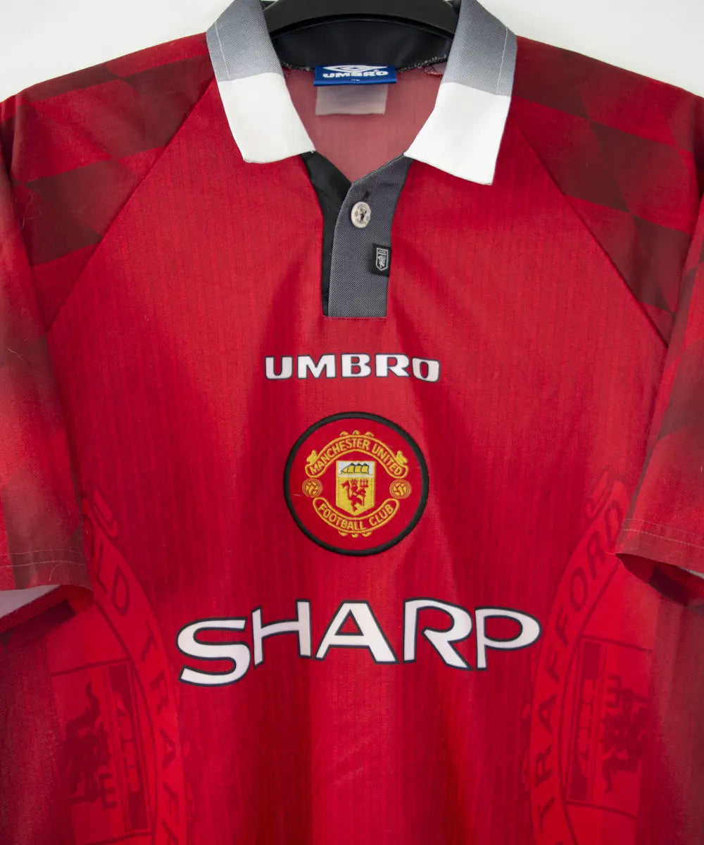 Maillot domicile vintage rouge de manchester united de la saison 1996-1998. On peut retrouver l'équipementier umbro et le sponsor sharp