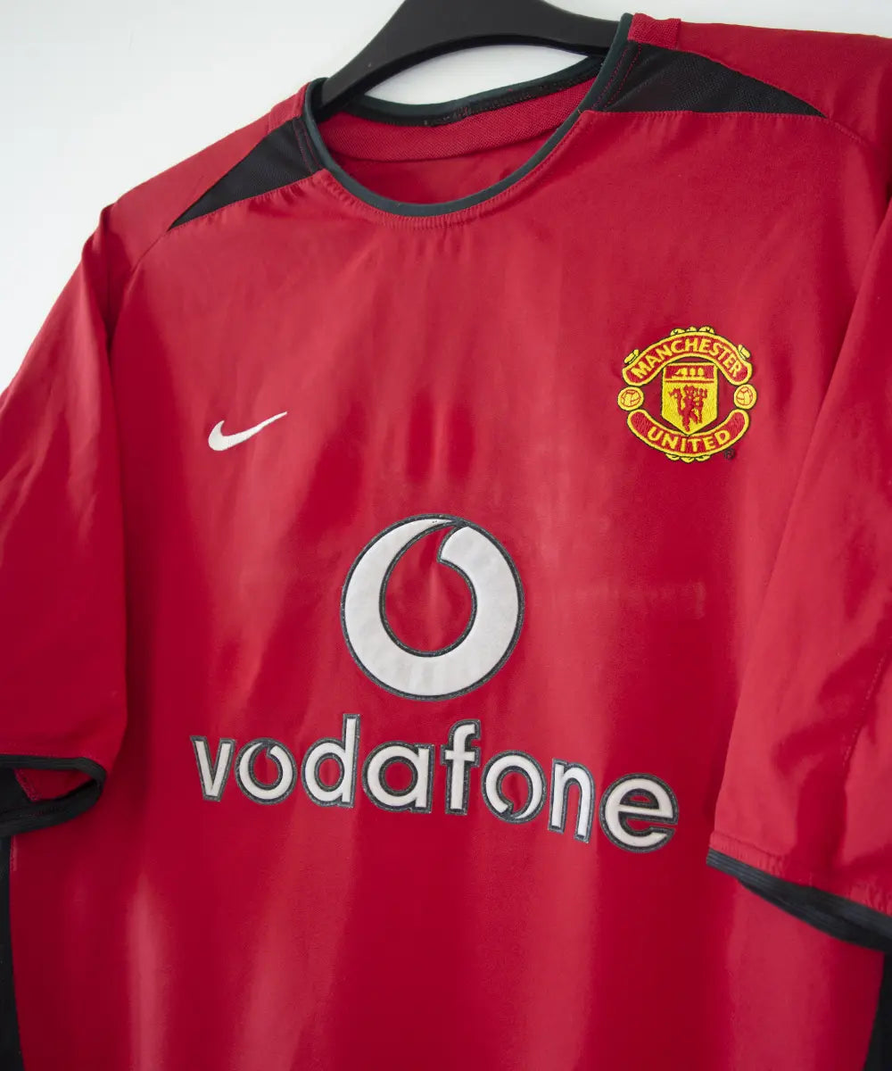 Maillot domicile rouge et noir de Manchester United de la saison 2002-2004. On peut retrouver l'équipementier nike et le sponsor Vodafone. Le maillot est floqué du numéro 7 Cristiano Ronaldo