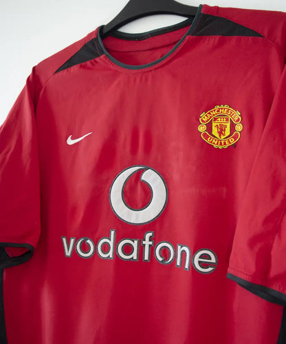 Maillot domicile rouge et noir de Manchester United de la saison 2002-2004. On peut retrouver l'équipementier nike et le sponsor Vodafone. Le maillot est floqué du numéro 7 Cristiano Ronaldo