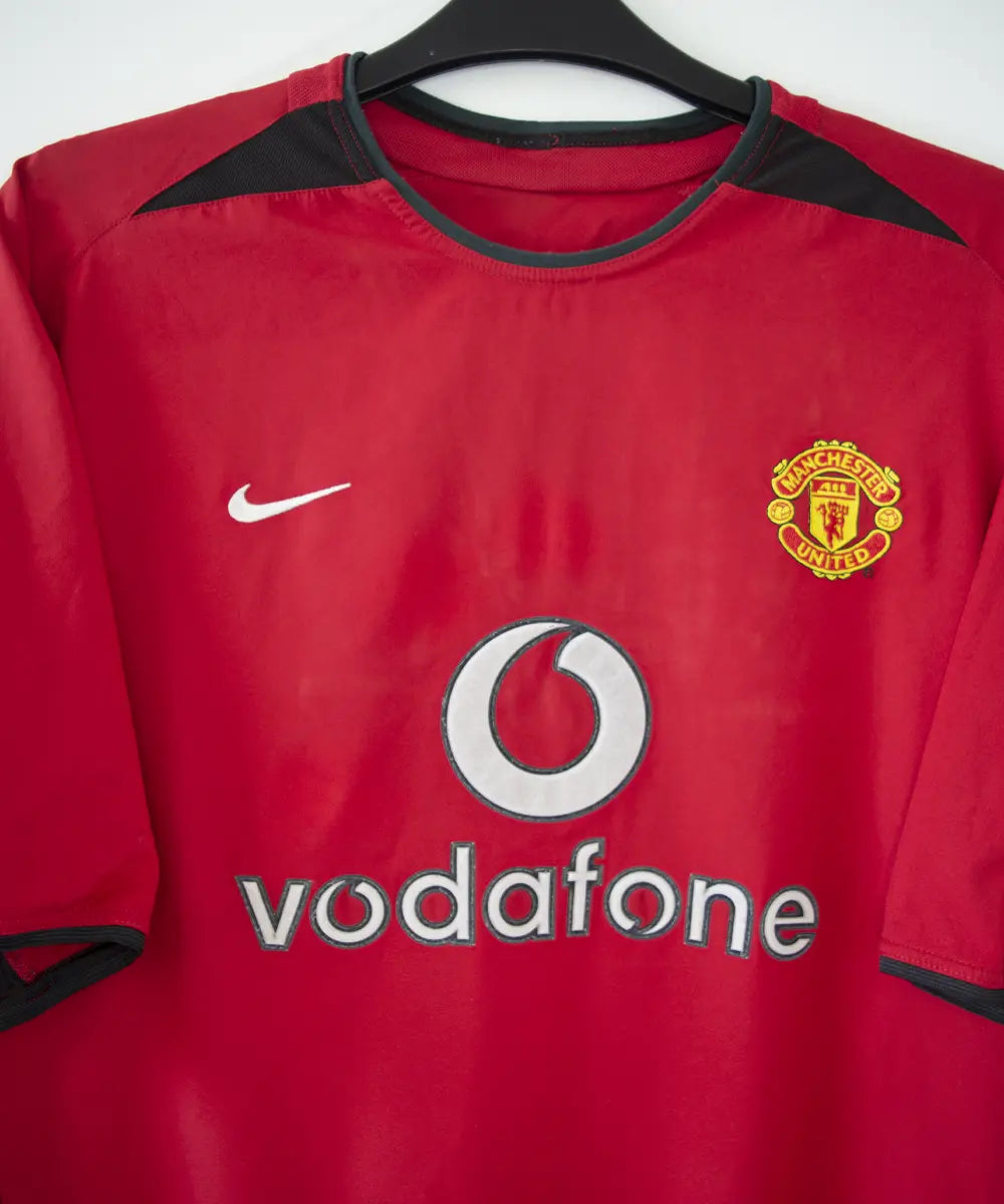 Maillot domicile rouge et noir de Manchester United de la saison 2002-2004. On peut retrouver l'équipementier nike et le sponsor Vodafone. Le maillot est floqué du numéro 7 Cristiano Ronaldo