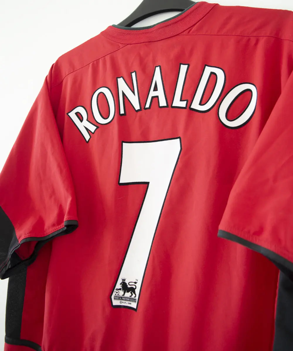 Maillot domicile rouge et noir de Manchester United de la saison 2002-2004. On peut retrouver l'équipementier nike et le sponsor Vodafone. Le maillot est floqué du numéro 7 Cristiano Ronaldo