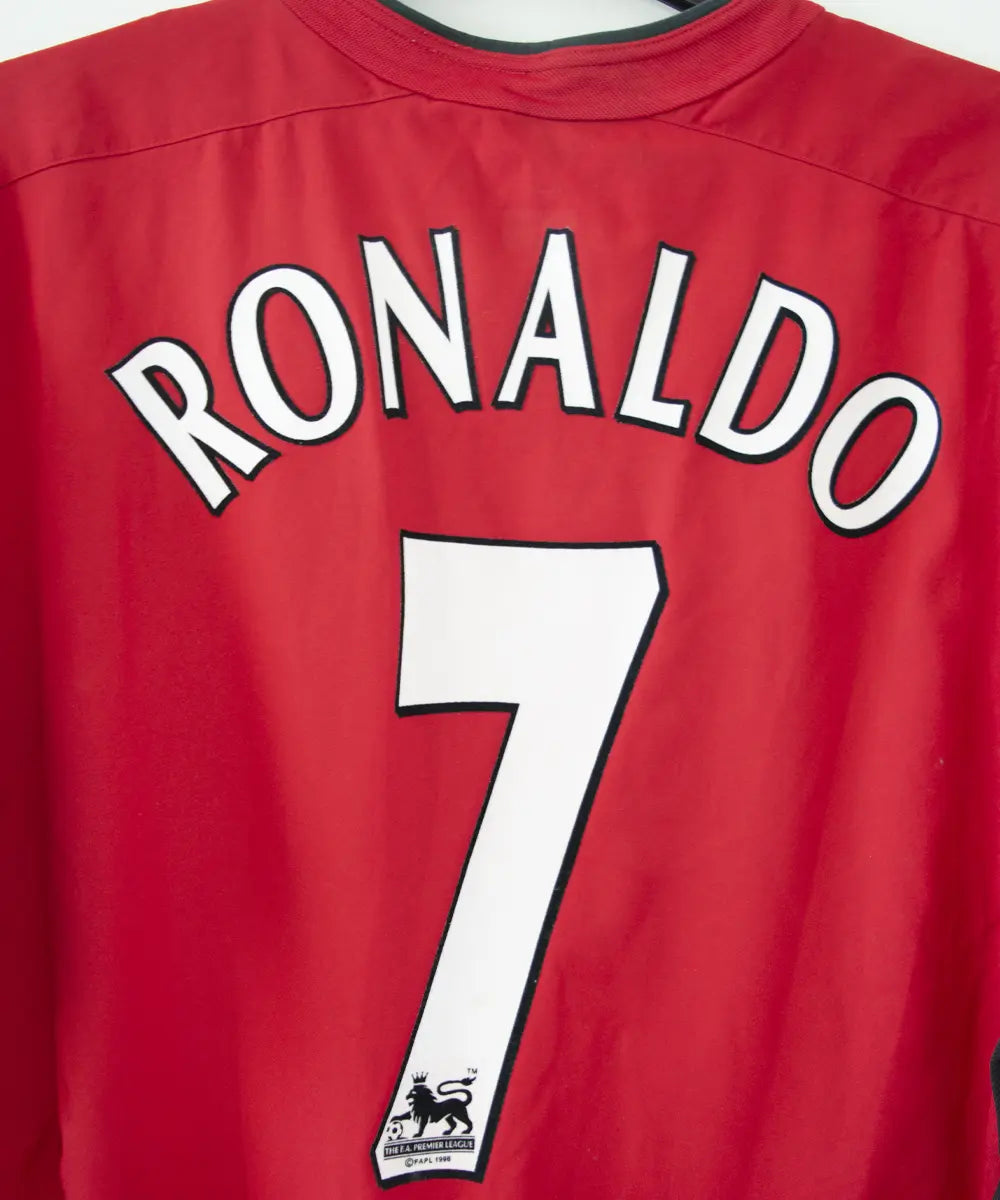 Maillot domicile rouge et noir de Manchester United de la saison 2002-2004. On peut retrouver l'équipementier nike et le sponsor Vodafone. Le maillot est floqué du numéro 7 Cristiano Ronaldo