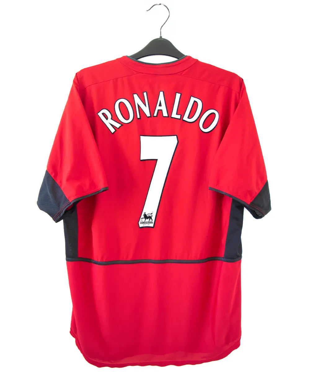 Maillot domicile rouge et noir de Manchester United de la saison 2002-2004. On peut retrouver l'équipementier nike et le sponsor Vodafone. Le maillot est floqué du numéro 7 Cristiano Ronaldo