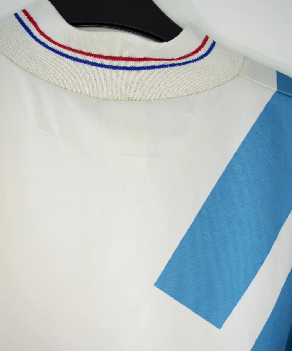 Maillot domicile blanc et bleu de l'om de la saison 1991-1992. On peut retrouver l'équipementier adidas et le sponsor Panasonic.