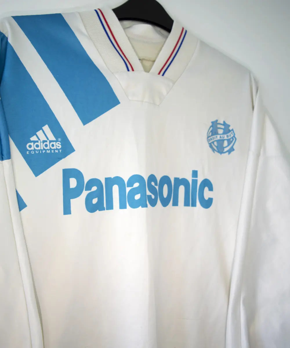 Maillot domicile blanc et bleu de l'om de la saison 1991-1992. On peut retrouver l'équipementier adidas et le sponsor Panasonic.