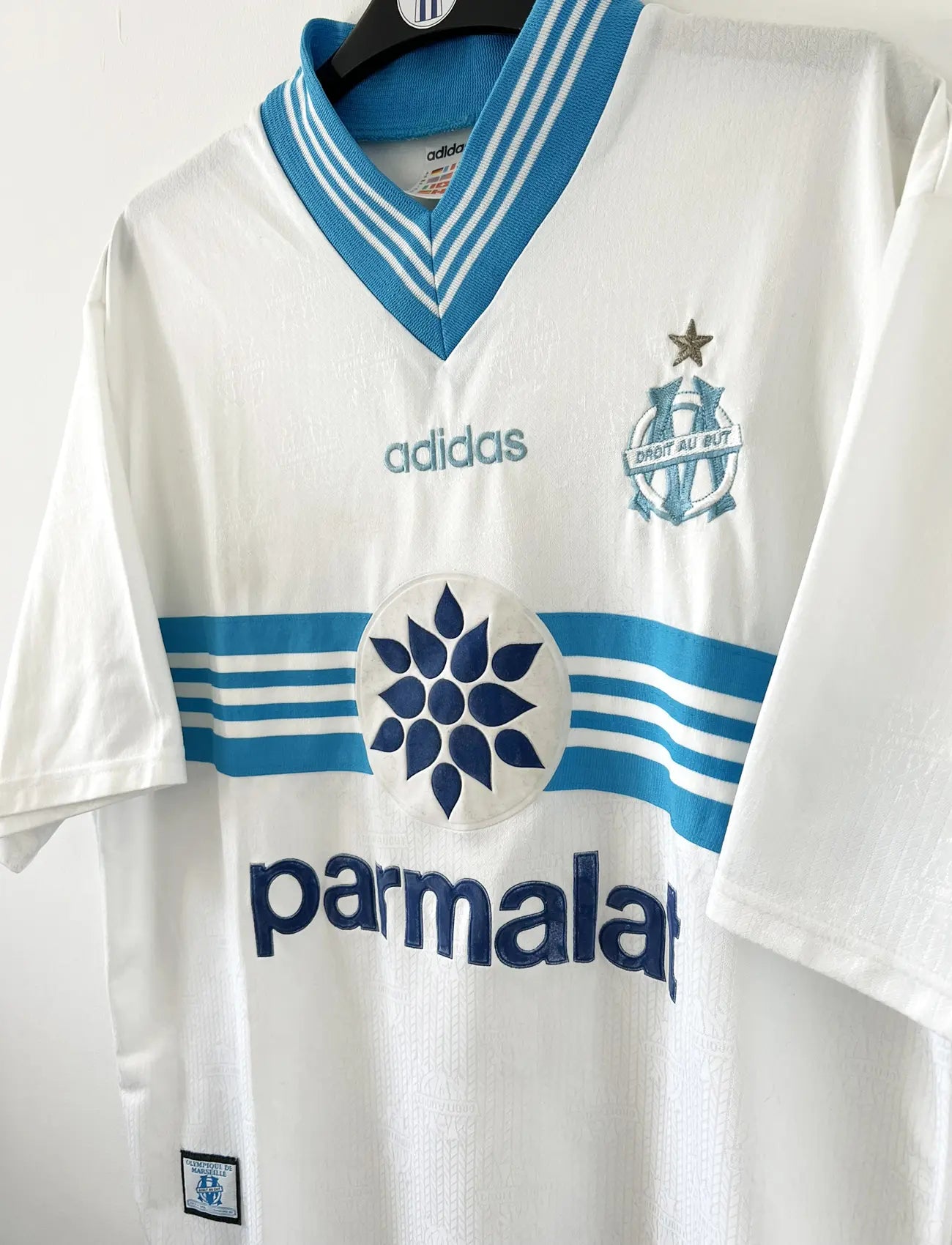 Maillot de foot vintage de l'OM de la saison 1996-1997. Le maillot est de couleur blanc et bleu. On peut retrouver l'équipementier adidas et le sponsor parmalat. Il s'agit d'un maillot authentique