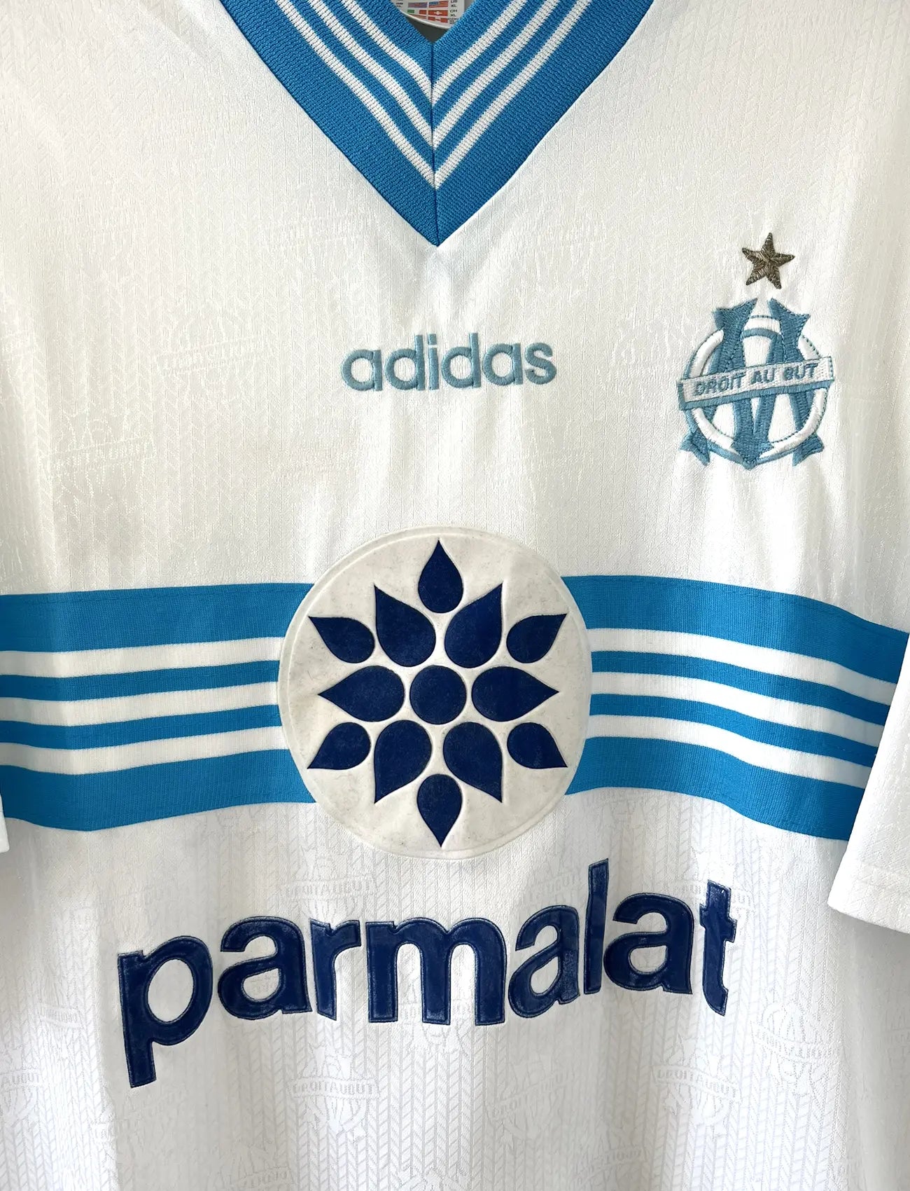 Maillot de foot vintage de l'OM de la saison 1996-1997. Le maillot est de couleur blanc et bleu. On peut retrouver l'équipementier adidas et le sponsor parmalat. Il s'agit d'un maillot authentique