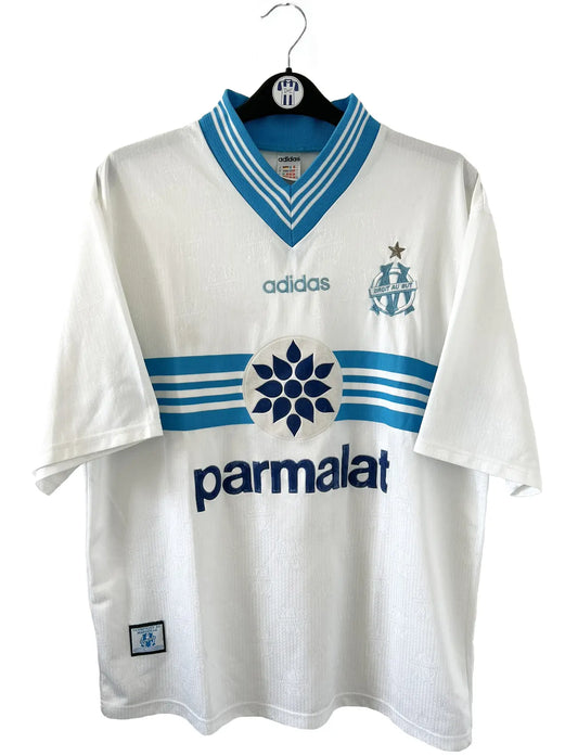 Maillot de foot vintage de l'OM de la saison 1996-1997. Le maillot est de couleur blanc et bleu. On peut retrouver l'équipementier adidas et le sponsor parmalat. Il s'agit d'un maillot authentique