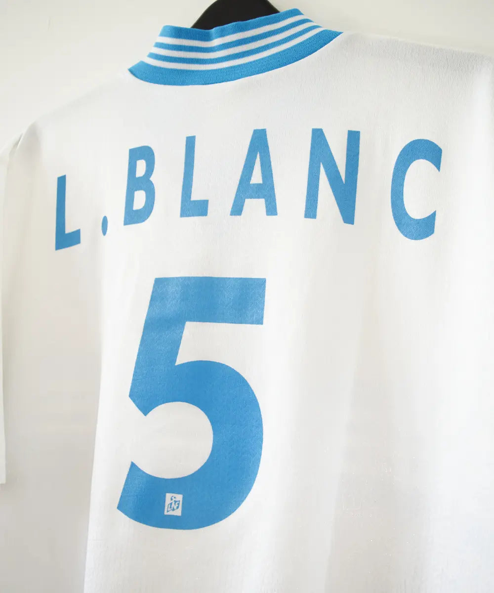 Maillot domicile blanc et bleu de l'olympique de marseille de la saison 1997-1998. Le maillot est floqué du numéro 5 Laurent Blanc. Sur cette photo on peut voir le flocage de près