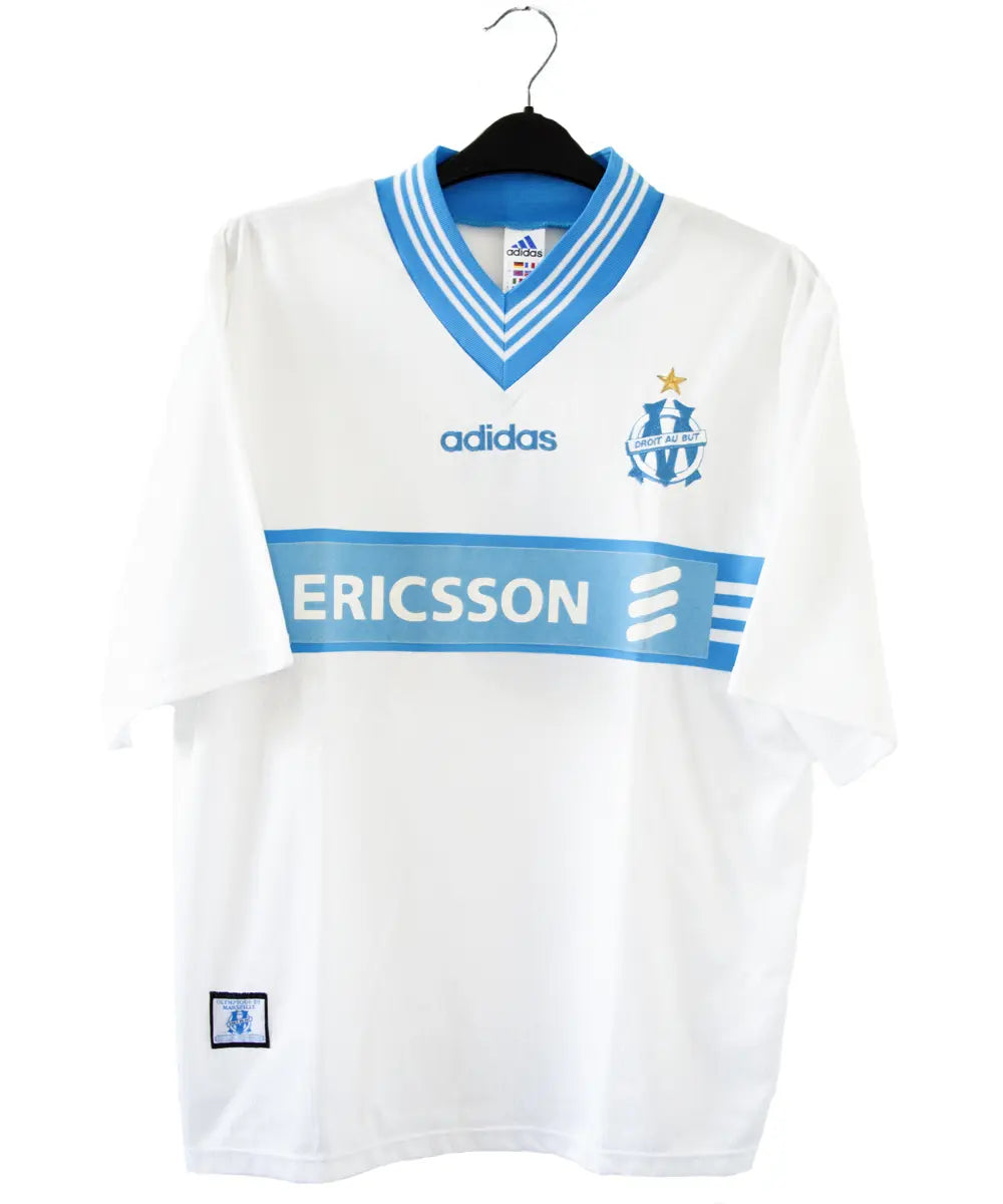 Maillot domicile blanc et bleu de l'olympique de marseille de la saison 1997-1998. Le maillot est floqué du numéro 5 Laurent Blanc. Sur cette photo on peut voir le devant du maillot avec sponsor ericsson et l'équipementier adidas