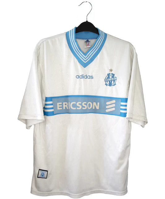 Maillot vintage domicile banc et bleu de l'OM de la saison 1997-1998. On peut retrouver l'équipementier adidas et le sponsor ericsson