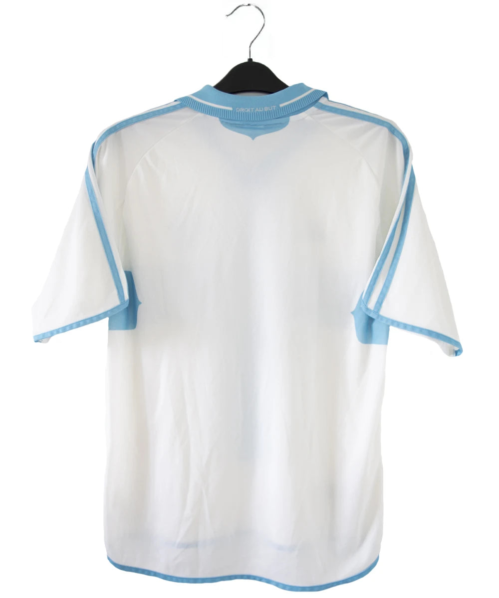 Maillot de foot vintage de l'om de la saison 2000-2001. Le maillot est de couleur blanc et bleu. On peut retrouver l'équipementier adidas et le sponsor ericsson. Ils s'agit d'un maillot authentique