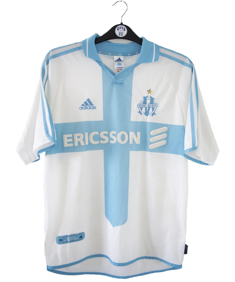 Maillot de foot vintage de l'om de la saison 2000-2001. Le maillot est de couleur blanc et bleu. On peut retrouver l'équipementier adidas et le sponsor ericsson. Ils s'agit d'un maillot authentique