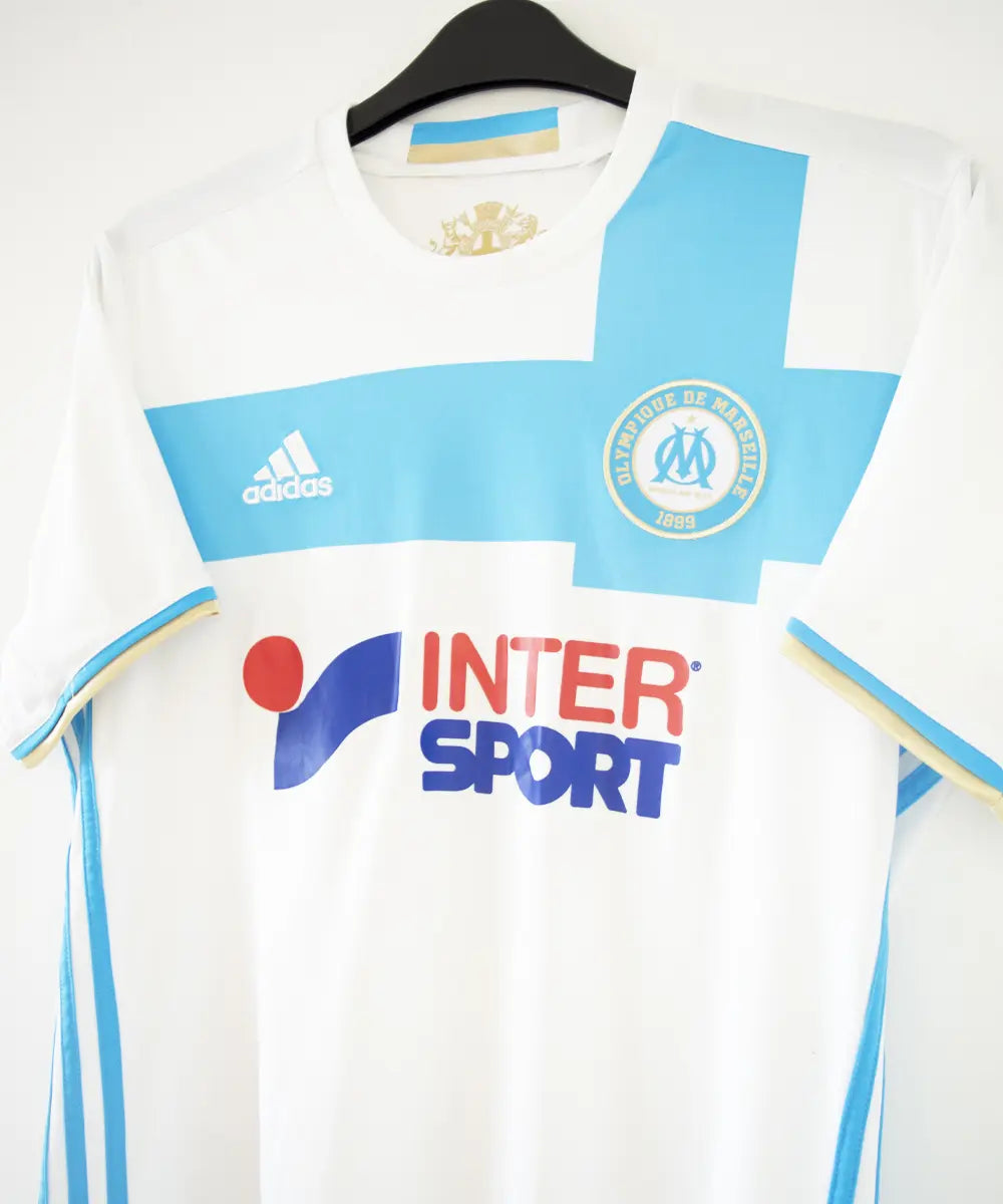 Maillot domicile OM 2016-2017 bleu et blanc. On peut retrouver l'équipementier adidas et le sponsor intersport