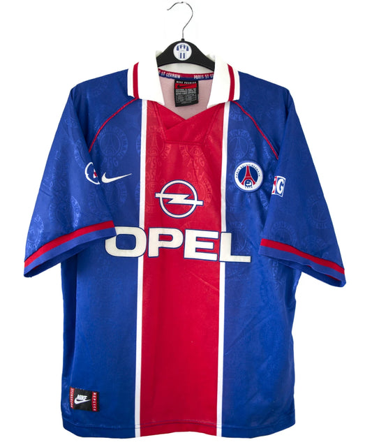 Maillot de foot vintage bleu blanc et rouge du psg de la saison 1996/1997. On peut retrouver l'équipementier nike et le sponsor opel. Il s'agit d'un maillot authentique d'époque