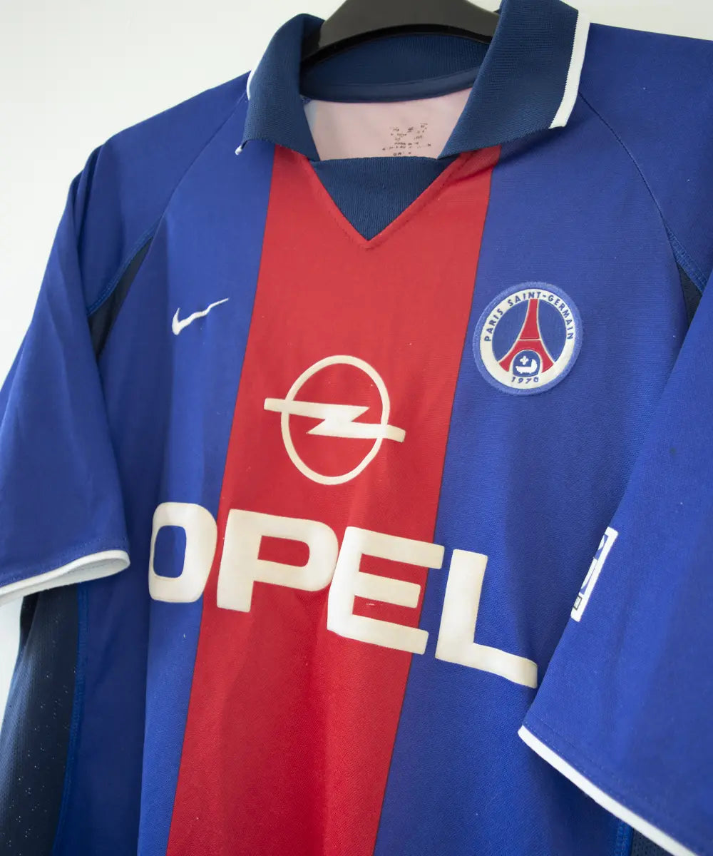 Maillot authentique domicile du PSG de la saison 2000-2001. Le maillot est de couleur bleu et rouge. On peut retrouver l'équipementier nike et le sponsor opel en feutrine. Le maillot est floqué du numéro 10 okocha. Sur cette photo on peut voir le maillot de côté