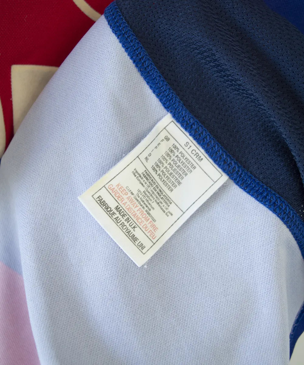 Maillot authentique domicile du PSG de la saison 2000-2001. Le maillot est de couleur bleu et rouge. On peut retrouver l'équipementier nike et le sponsor opel en feutrine. Le maillot est floqué du numéro 10 okocha. Sur cette photo on peut voir l'étiquette d'authenticité du maillot Made in UK