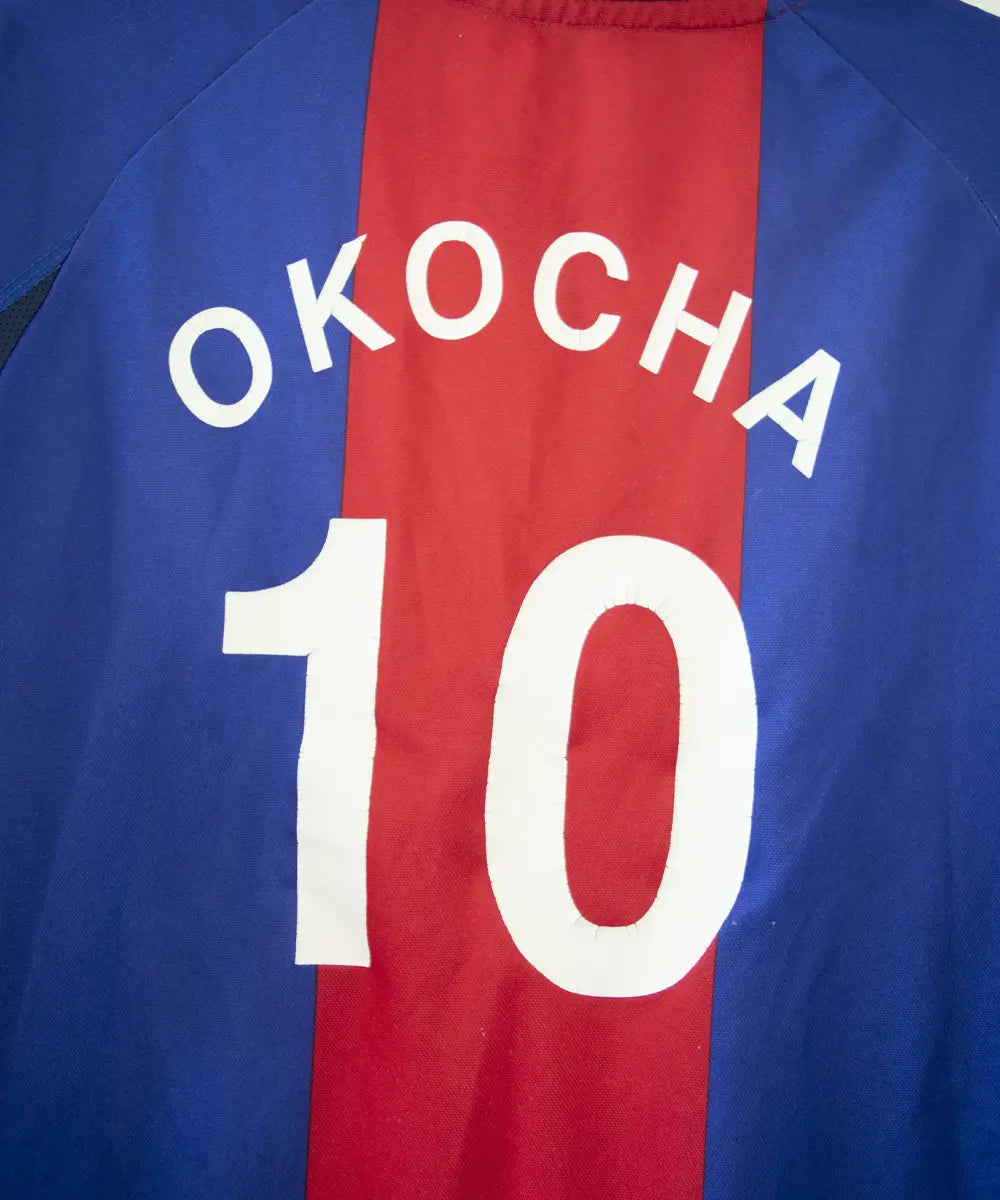 Maillot authentique domicile du PSG de la saison 2000-2001. Le maillot est de couleur bleu et rouge. On peut retrouver l'équipementier nike et le sponsor opel en feutrine. Le maillot est floqué du numéro 10 okocha. Sur cette photo on peut voir le flocage de près