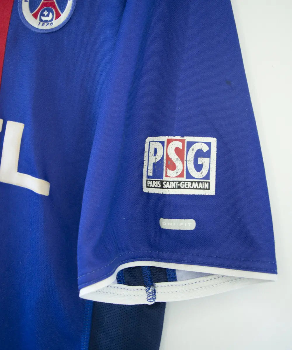 Maillot authentique domicile du PSG de la saison 2000-2001. Le maillot est de couleur bleu et rouge. On peut retrouver l'équipementier nike et le sponsor opel en feutrine. Le maillot est floqué du numéro 10 okocha. Sur cette photo on peut voir le logo du PSG sur la manche