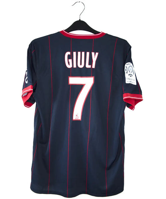 Maillot domicile du psg de la saison 2009 2010. Le maillot est de couleur bleu avec des rayures rouges. On peut retrouver l'équipementier nike, le sponsor fly emirates et le sponsor poweo. Le maillot est floqué ludovic Giuly. Sur cette photo on peut voir le flocage