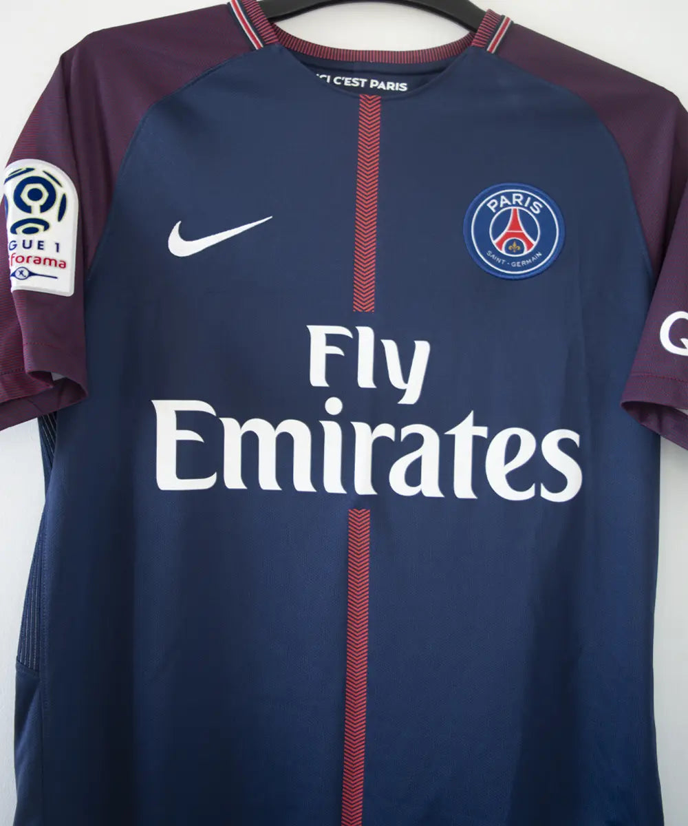 Maillot authentique du psg de la saison 2017-2018. Le maillot est de couleur bleu et rouge. On peut retrouver sur le maillot l'équipementier nike et le sponsor fly emirates et QNB. Le maillot est floqué du numéro 10 neymar. Sur cette photo on peut voir le devant du maillot