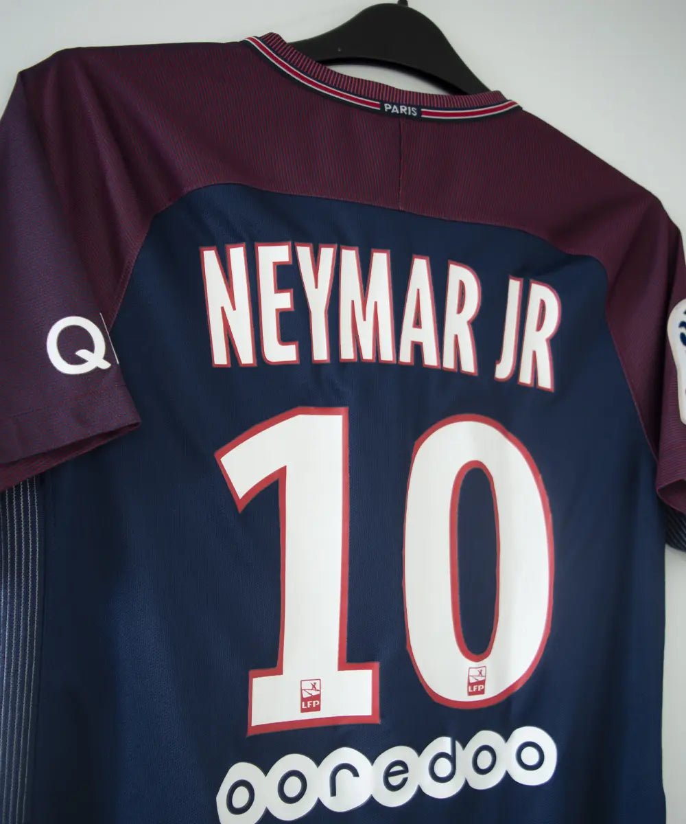 Maillot domicile bleu et rouge du psg de la saison 2017-2018. On peut retrouver l'équipementier nike et le sponsor fly emirates. Le maillot est floqué du numéro 10 Neymar