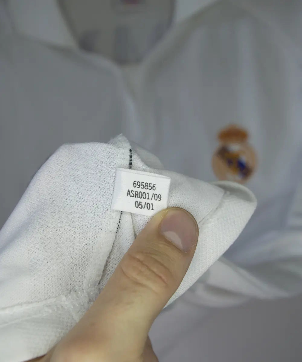 Maillot de foot vintage blanc domicile du real madrid de la saison 2001-2002. Il s'agit du maillot édité pour le centenaire. On peut retrouver l'équipementier adidas et le sponsor real madrid.com. Le maillot est floqué du numéro 5 Zidane. Le maillot comporte l'étiquette 695856 ASR001/09