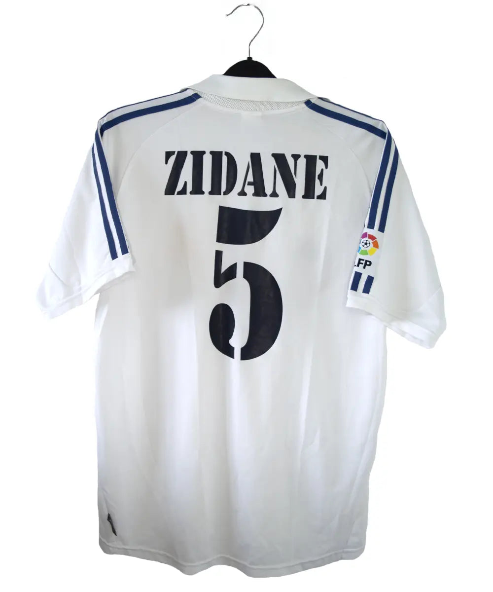 Maillot de foot vintage blanc domicile du real madrid de la saison 2001-2002. Il s'agit du maillot édité pour le centenaire. On peut retrouver l'équipementier adidas et le sponsor real madrid.com. Le maillot est floqué du numéro 5 Zidane. Le maillot comporte l'étiquette 695856 ASR001/09