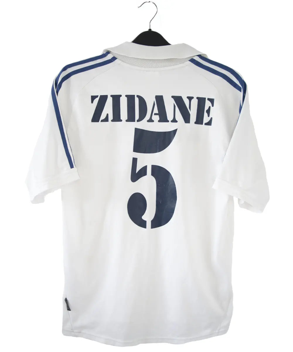 Maillot de foot vintage blanc et bleu du real madrid de la saison 2001-2002. On peut retrouver l'équipementier adidas et le sponsor real madrid.com. Le maillot est flqqué du numéro 5 Zinedine Zidane. Il s'agit d'un maillot authentique.