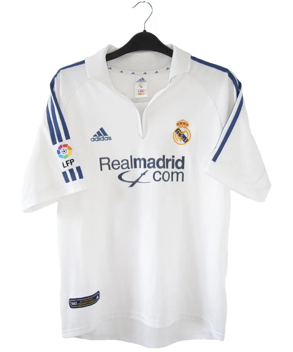 Maillot de foot vintage blanc et bleu du real madrid de la saison 2001-2002. On peut retrouver l'équipementier adidas et le sponsor real madrid.com. Le maillot est flqqué du numéro 5 Zinedine Zidane. Il s'agit d'un maillot authentique.