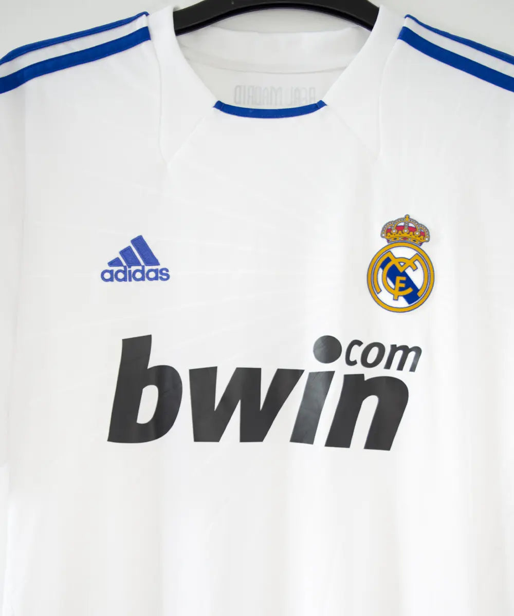 Maillot domicile du real madrid de la saison 2010-2011. Le maillot est floqué du numéro 7 cristiano ronaldo. Sur ce maillot on peut retrouver le sponsor bwin et l'équipementier adidas ainsi que le patch de la LFP. Sur cette photo on peut voir le devant du maillot de près