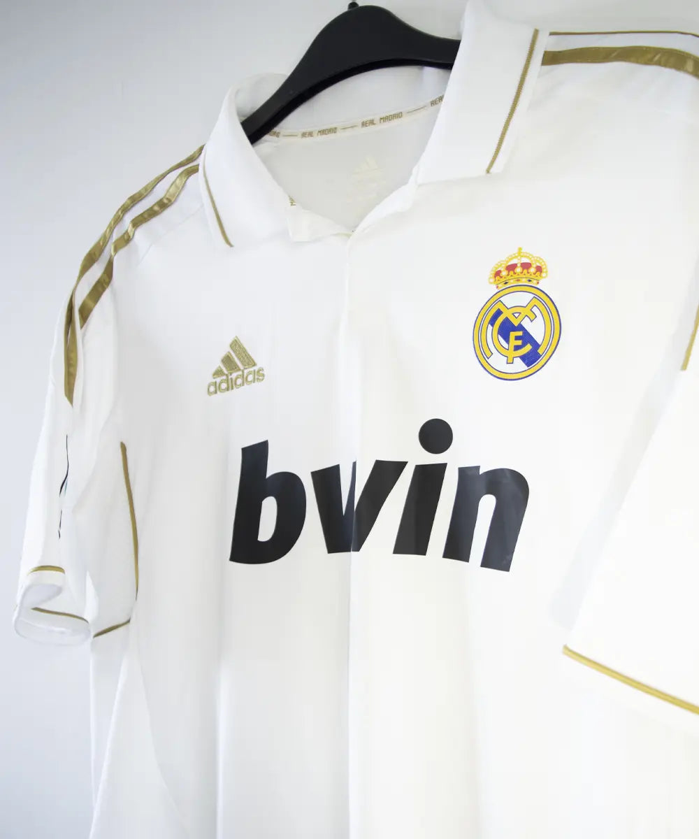 Maillot domicile du real madrid de couleur blanc et or de la saison 2011-2012. On peut retrouver l'équipementier adidas et le sponsor bwin. Le maillot est floqué du numéro 7 Cristiano Ronaldo. L'étiquette du maillot comporte les numéro V13659