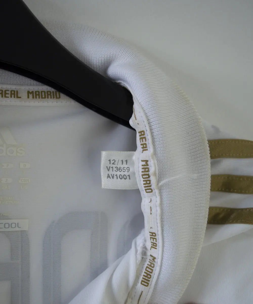 Maillot domicile du real madrid de couleur blanc et or de la saison 2011-2012. On peut retrouver l'équipementier adidas et le sponsor bwin. Le maillot est floqué du numéro 7 Cristiano Ronaldo. L'étiquette du maillot comporte les numéro V13659