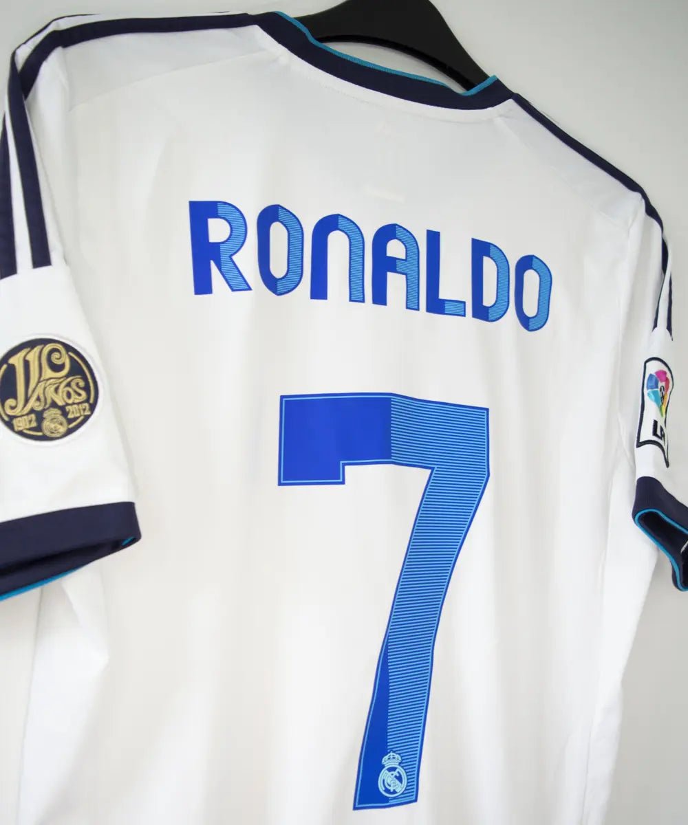 Maillot blanc et bleu du real madrid de la saison 2012-2013. On peut retrouver sur le maillot le sponsor bwin et l'équipementier adidas. Le maillot porte aussi le patch des 110 ans du real et le patch de la LFP. Sur cette photo on peut voir le flocage de côté du maillot du numéro 7 cristiano ronaldo