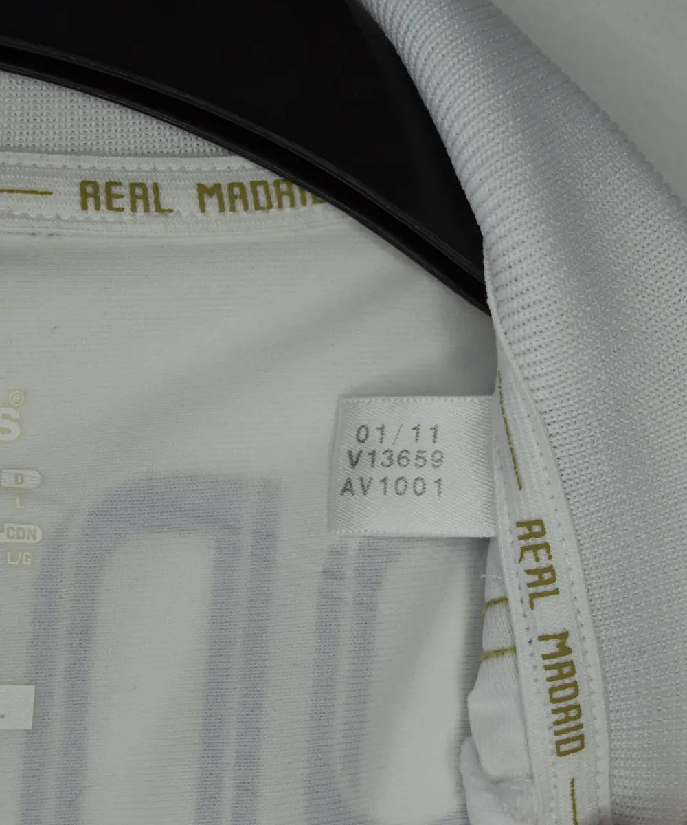 Maillot domicile du real madrid de couleur blanc et or de la saison 2011-2012. On peut retrouver l'équipementier adidas et le sponsor bwin. Le maillot est floqué du numéro 7 Cristiano Ronaldo. L'étiquette du maillot comporte les numéro V13659