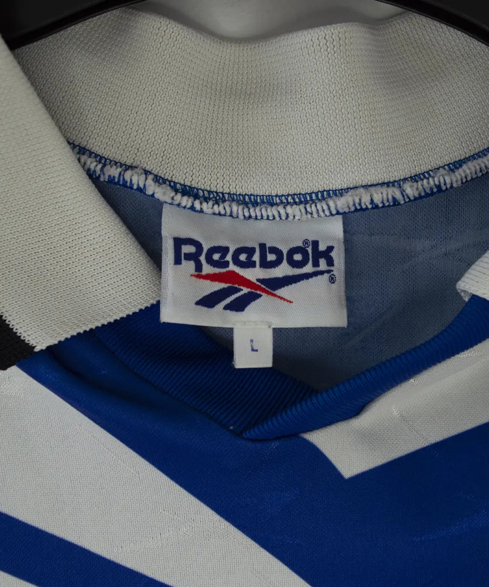Maillot domicile bleu et blanc du sc bastia de la saison 1995-1997. On peut retrouver l'équipementier reebok, et le sponsor nouvelles frontières. Sur cette photo on peut voir l'étiquette reebok du maillot