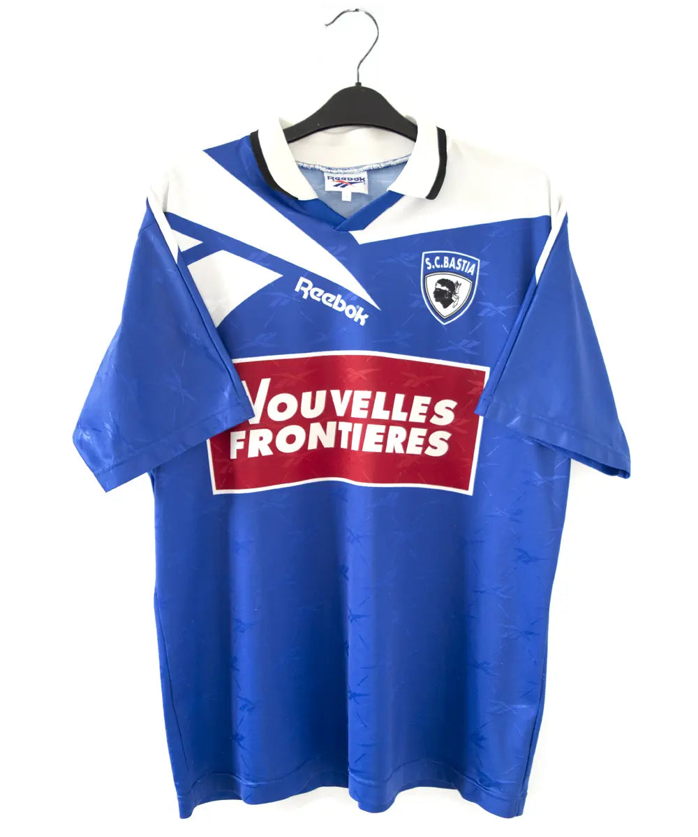 Maillot domicile bleu et blanc du sc bastia de la saison 1995-1997. On peut retrouver l'équipementier reebok, et le sponsor nouvelles frontières
