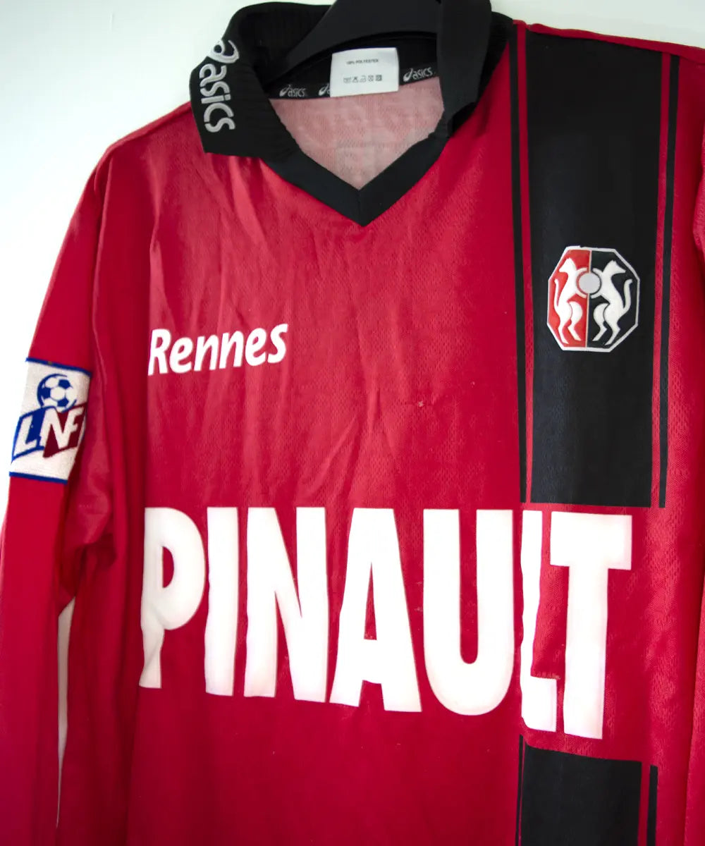Maillot domicile du stade rennais porté lors de la saison 2000-2001 par Echouafni. Le maillot est de couleur rouge et noir. On peut retrouver l'équipementier asics et les sponsor Pinault et Finaref.