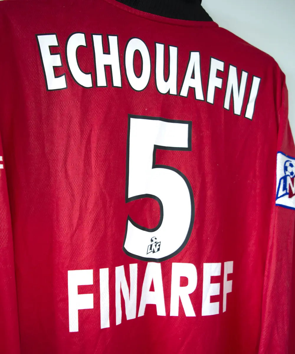 Maillot domicile du stade rennais porté lors de la saison 2000-2001 par Echouafni. Le maillot est de couleur rouge et noir. On peut retrouver l'équipementier asics et les sponsor Pinault et Finaref.